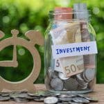 glass jar bottle labeled as investment with full of coins and ba